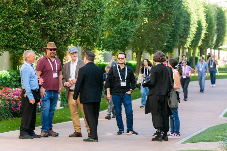 ASG’s Hamid “Gadget” Hopkins, Dan Levy and Dave Van Hoy talk with attendees on a tree-lined walkway at Sony Pictures Studios.